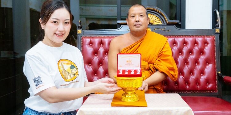 พระครูวินัยธรจีรเดช มอบเหรียญสมเด็จพระเจ้าตากสิน รุ่นมหาเศรษฐี แก่ คุณฐนนันท์ ผู้เป็นต้นเสียงในแอปพลิเคชัน แอพเดียวเที่ยวทั่ววัดอรุณ ภาคภาษาจีน